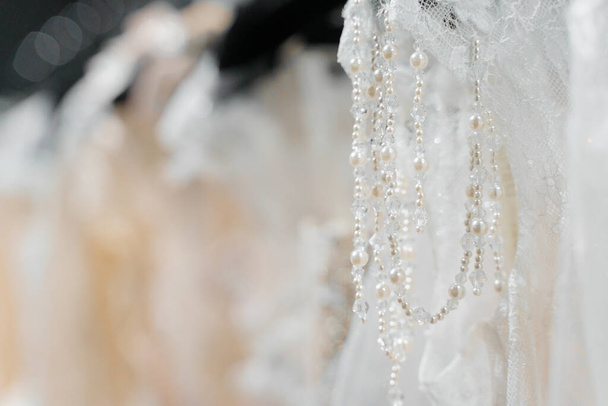 シルクシフォン、チュールとレースで作られたウェディングドレス。ウェディングサロンでハンガーに美しいホワイトクリームブライダルドレス。パールとクリスタルは、ウェディングドレスの繊細な色の袖に依存します。 - 写真・画像