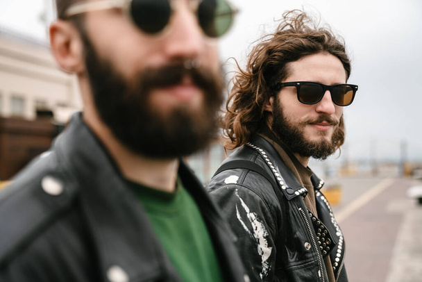 Photo closeup of bearded pleased men bikers in sunglasses posing and looking at camera together outdoors - Fotoğraf, Görsel