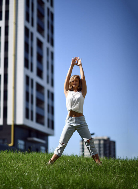 Young woman doing yoga stretching exercises in urban modern city park - Fotó, kép
