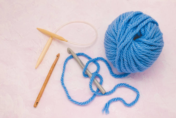 編み物用の毛糸のボール。かぎ針編みのフックと編み物で。ピンクの背景. - 写真・画像