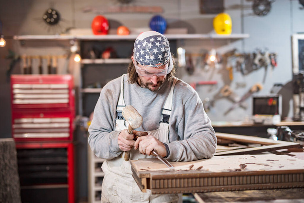 Erkek marangoz antika bir atölyede eski ahşap üzerinde çalışıyor.. - Fotoğraf, Görsel