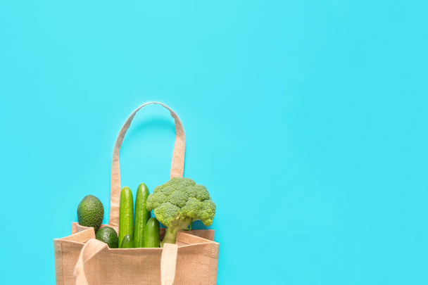 Verduras verdes en bolsa de compras reciclada ecológica sobre fondo azul. Vista superior, plano, espacio para copiar
 - Foto, Imagen