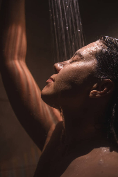 若いきれいな女性がシャワーを浴びてる。ライトが低い。閉鎖 - 写真・画像