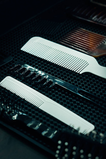           white and brown combs in a barber shop on a black table. Hair styling. Professional barber tools.                      - Foto, afbeelding