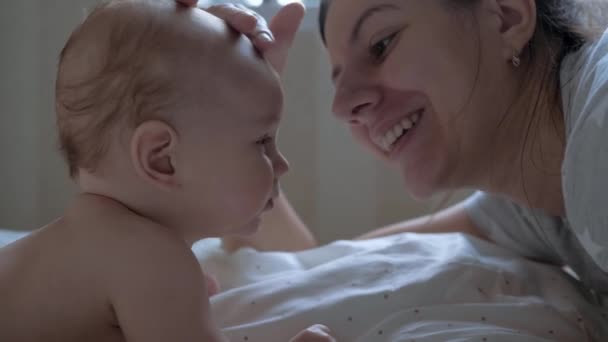 Mãe e seu bebê recém-nascido mentem em seu estômago em uma cama oposta um ao outro
 - Filmagem, Vídeo