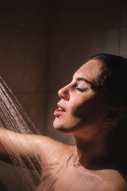 fiatal csinos nő zuhanyozik. alacsony fény. közelkép - Fotó, kép