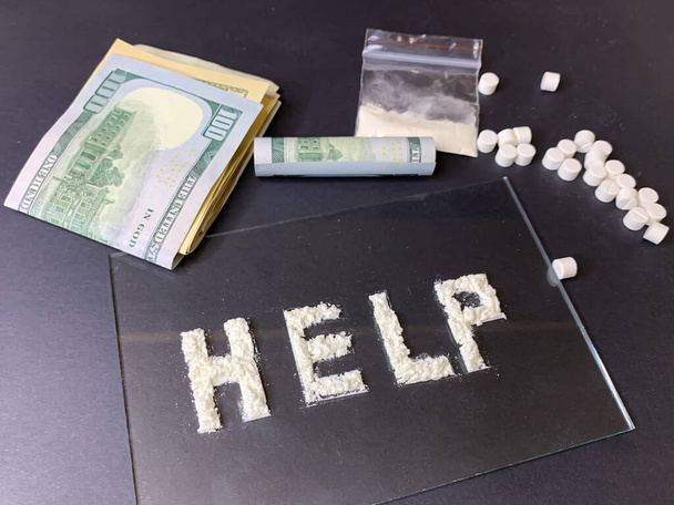 Haplar, Amerikan banknotları ve gri arka planda kokain. Uyuşturucu konseptini durdur. Kokainle yazılmış bir "yardım" kelimesi. Resim yükle. - Fotoğraf, Görsel