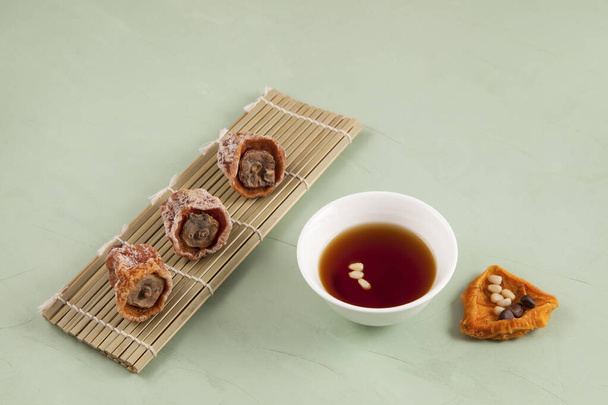 Sujeonggwa - Korean punch with cinnamon and dried persimmons. Dark reddish brown in color, it is made from gotgam (dried persimmon) and is often garnished with pine nuts. It is drunk chilled. - Фото, зображення