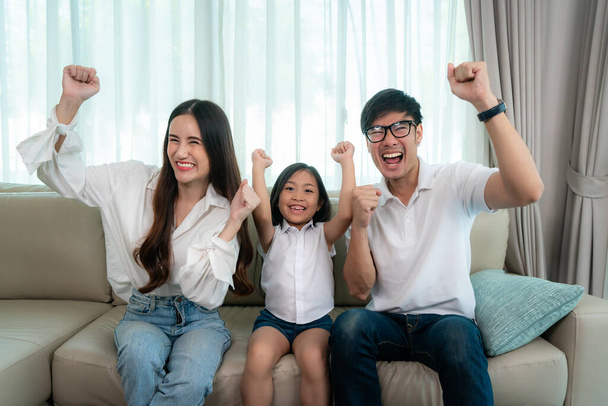 Őszinte boldog ázsiai család apa, anya és lánya élvezze a hétvégi tevékenység több időt otthon, és ezért valószínűleg több időt a televízió előtt - Fotó, kép