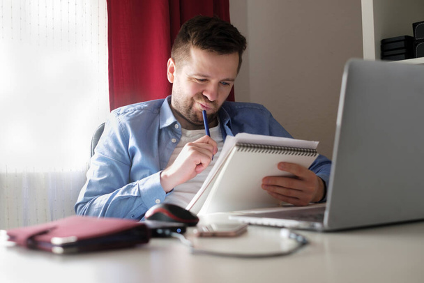 Young caucasian man working from home reading documents - Fotó, kép