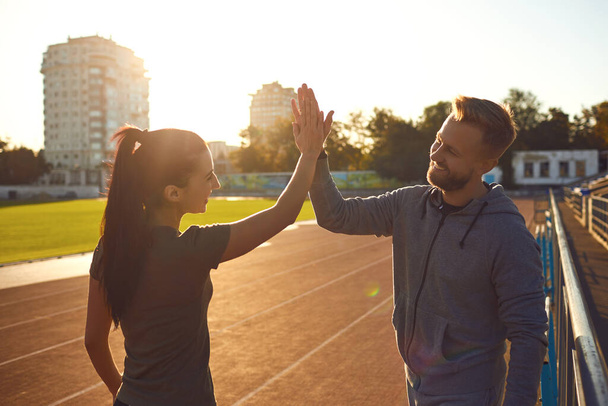A young couple of athletes raised their hands up in the morning at dawn. - 写真・画像