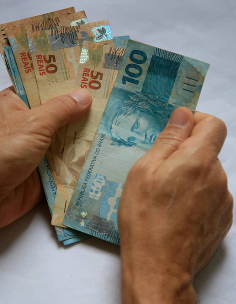 salvador, bahia / brésil - 28 mars 2020 : les mains de la femme tiennent des billets reais, monnaie utilisée au Brésil. Légende locale * * * *
 - Photo, image