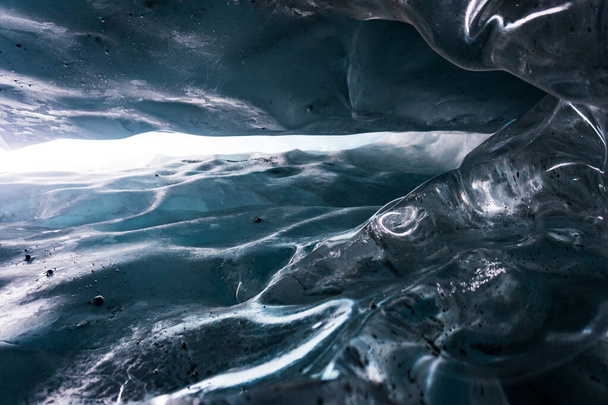 Nahaufnahme aus dem Inneren einer Eishöhle am Matanuska-Gletscher in Alaska. Details der Oberfläche des Eises; Textur. Ein Blick nach oben. Aufgenommen während einer Wanderung in den Winterferien. Gegen das Licht. - Foto, Bild