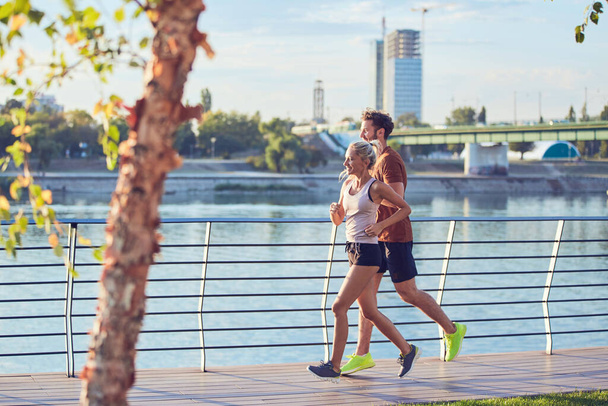 川の近くの都市環境で現代の女性と男性のジョギング/運動. - 写真・画像