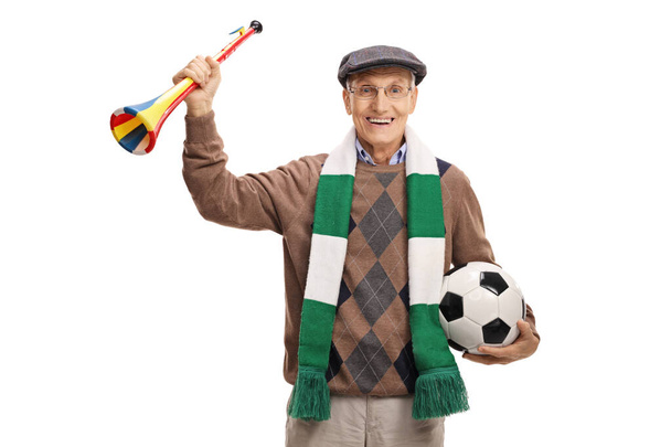 Elderly man with a soccer ball and a horn smiling at the camera isolated on white background - Foto, imagen