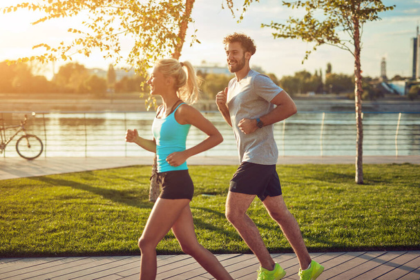 Donna moderna e uomo che fanno jogging / esercizio in un ambiente urbano vicino al fiume. - Foto, immagini