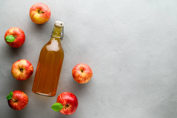 Kombucha fermentato fatto in casa in una bottiglia e mele rosse su uno sfondo di pietra grigia. Una bevanda rinfrescante probiotica sana è il kombucha
. - Foto, immagini