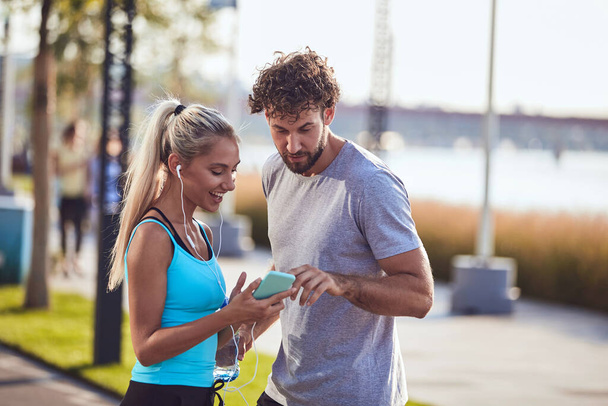 Couple moderne faisant une pause sur le trottoir pendant le jogging / exercice. - Photo, image
