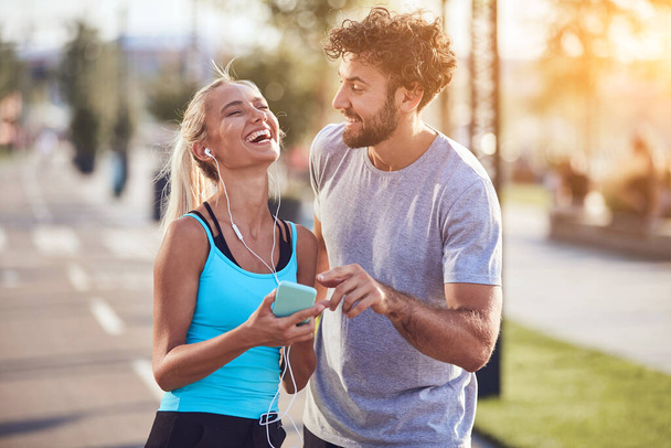 Modern couple making pause on the sidewalk during jogging / exercise. - Photo, Image
