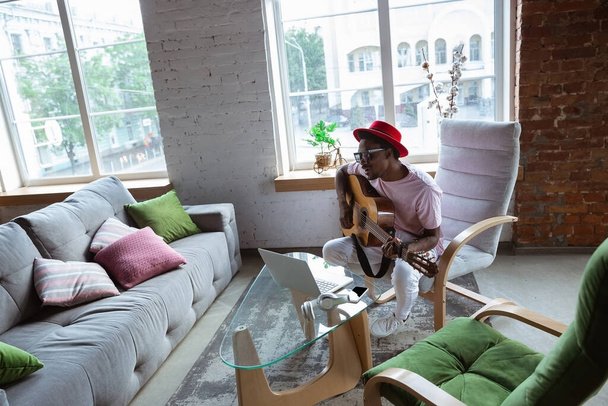 African-american musician playing guitar during online concert at home isolated and quarantined, impressive improvising - Photo, Image