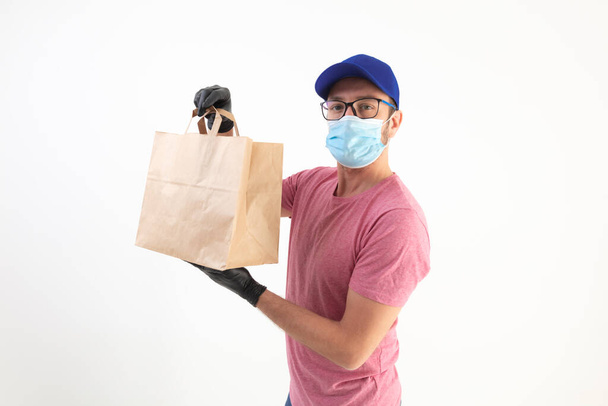 Repartidor con máscara protectora sosteniendo bolsa de papel con comestibles. - Foto, Imagen