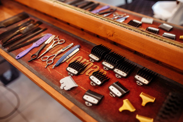 Trimmer nozzles are laid out on a wooden table in a barbershop. Professional barber tool kit. Hairdressing equipment. - Photo, Image