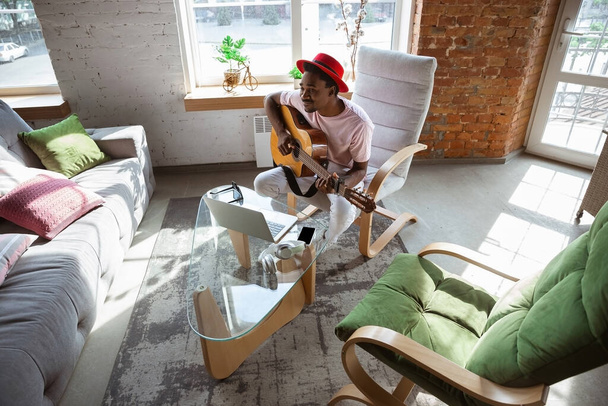 African-american musician playing guitar during online concert at home isolated and quarantined, impressive improvising - Фото, зображення