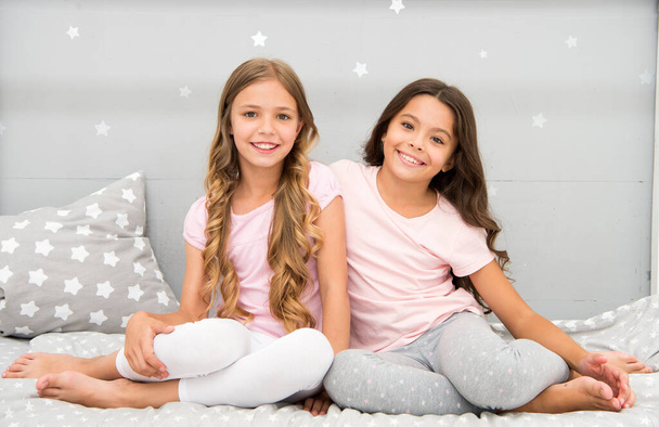 Happy morning. Children in pajamas. Stay at home. Pajamas all day. Cute cozy bedroom for small girls. Sisters having fun bedroom interior. Childhood concept. Bedroom place relax and enjoy rest - Foto, Bild