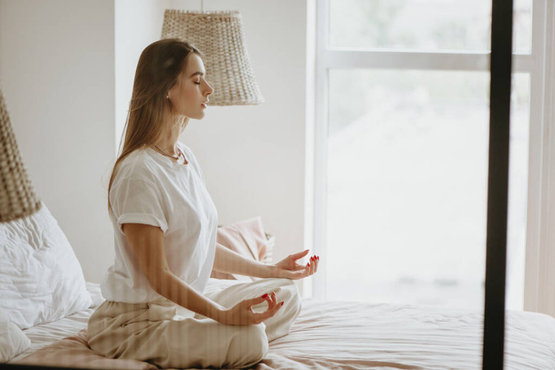 Young woman practicing meditation on bed. - Foto, Imagen