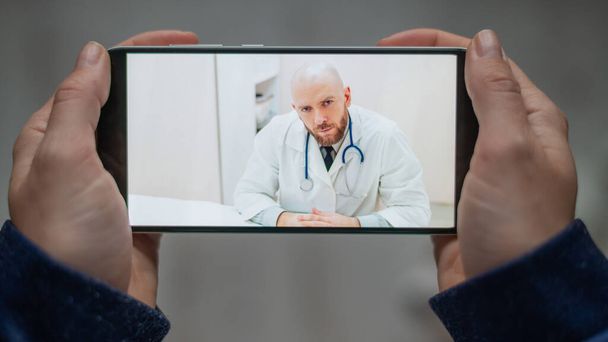 Online medicine. The patient talks to the doctor via video link while at home. A man gives a remote medical consultation on a smartphone. A woman is sick at home and calls the therapist. - Foto, imagen