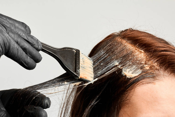 Um cabeleireiro que pinta um cabelo a mulheres pela escova preta. Brunet modificando uma cor de cabelo. Marido tintas cabelo para sua esposa
. - Foto, Imagem