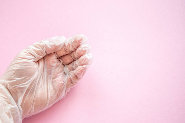 Flat lay female hand in a medical glove with palm up on a pink background. Asking gesture. Donations and help to doctors on time coronovirus pandemic concept. Top view - Photo, Image