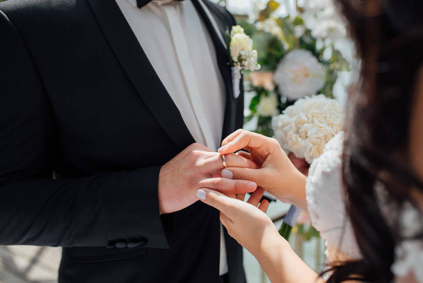 beautiful girl bride in wedding white dress puts on the groom's finger the wedding gold ring. - Fotografie, Obrázek