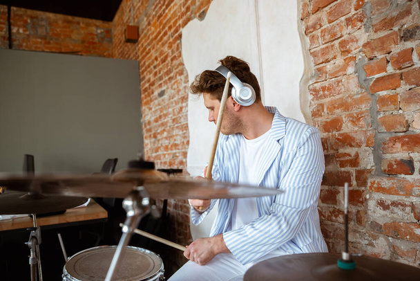 Caucasian musician playing drumms during online concert with the band at home isolated and attented, smiling, cheerful - Valokuva, kuva