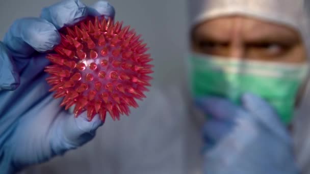 4K, Male scientific with protective suit holding a Coronavirus red model. Caucasian man with molecule of COVID-19. The concept of infecting or transmitting a virus between people.-Dan - Footage, Video