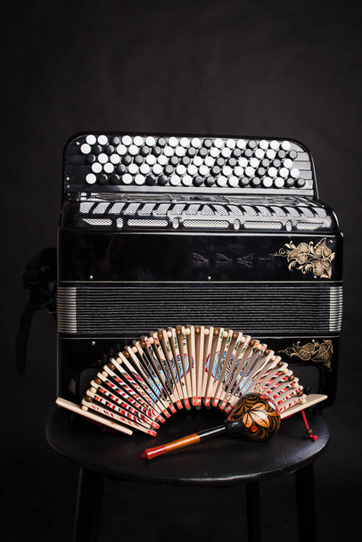 Instrumentos musicales populares rusos. Acordeón negro y sonajeros
 - Foto, imagen