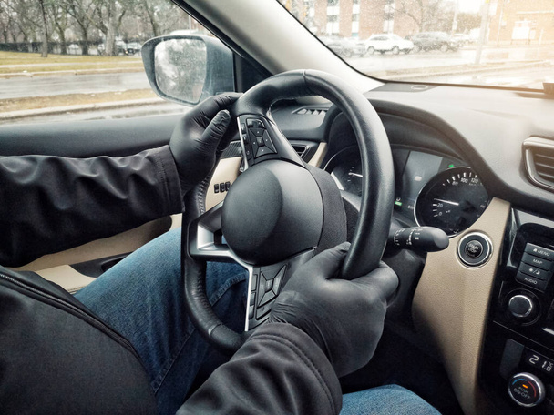 Siyah lateks eldivenli adam araba direksiyonu tutuyor. Koruyucu eldivenlerle insan ellerine yakın çekim. Coronavirus covid-19 salgın karantinasında önlem güvenliği. Sağlık koruması. - Fotoğraf, Görsel