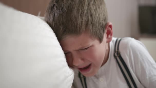 примхлива дитина, розчарована чоловіча дитина істерична і плаче через непорозуміння в сім'ї або депресії, сидячи в кімнаті біля дивана
 - Кадри, відео