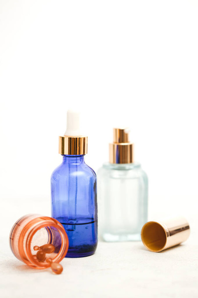 Set van kleurrijke glazen flessen met huidverzorgingsproducten op witte achtergrond met kopieerruimte. Gezichtsserums, -zuren en -verpakkingen voor etherische oliën. - Foto, afbeelding