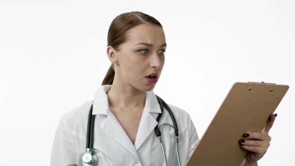 Médico femenino caucásico con estetoscopio sobre el cuello sostiene tableta y conmocionado - Imágenes, Vídeo