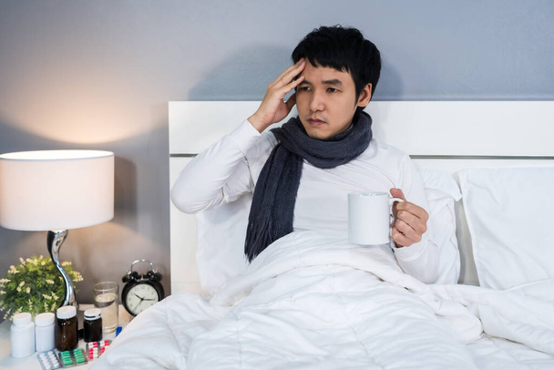 sick man headache and drinking a cup of hot water on a bed - Fotoğraf, Görsel