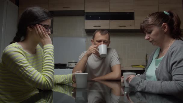 Familia discute problemas sentado en la noche sentado en una mesa en la cocina beber té
 - Metraje, vídeo