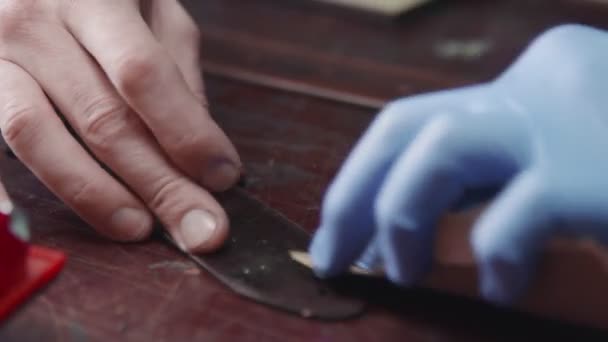 Professioneller Gerber schärft den Gürtel. Der Ledermeister bastelt einen Gürtel - Filmmaterial, Video