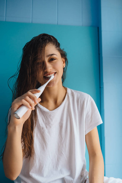 Genç ve güzel bir kadın diş fırçasıyla dişlerini fırçalıyor. - Fotoğraf, Görsel