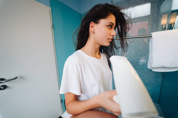 Retrato de mujer joven usando secador de pelo en el baño - Foto, imagen