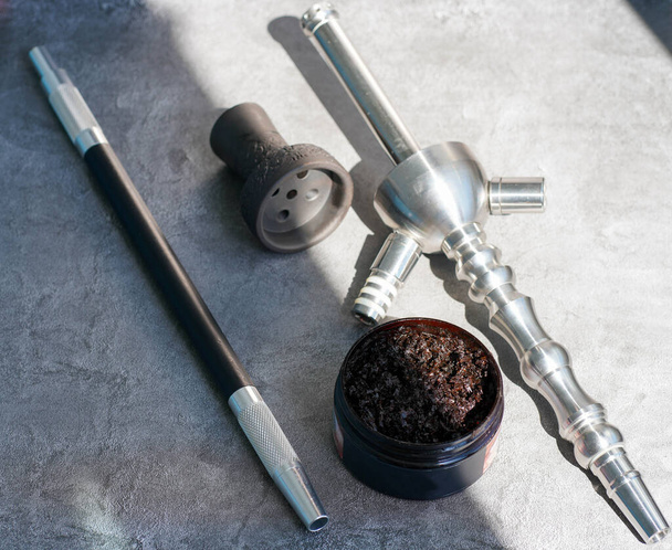 Steel hookah shisha, mouthpiece and clay bowl, tobacco on a gray concrete background. - Zdjęcie, obraz