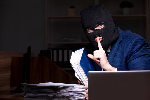Miespuolinen työntekijä varastaa tietoja toimistossa yöllä
 - Valokuva, kuva