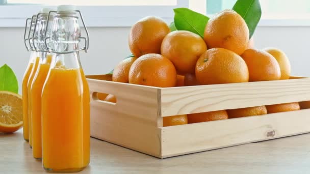 pile of fresh oranges in wooden box and glasses of juice - Footage, Video