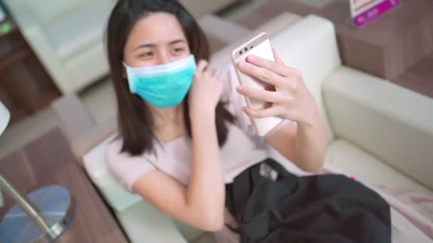 Asian Woman sit down video calling while wear mask, new normal life style, life relationship contact, during covid-19, video call isolation quarantine. social distancing, family quality time, above - Footage, Video