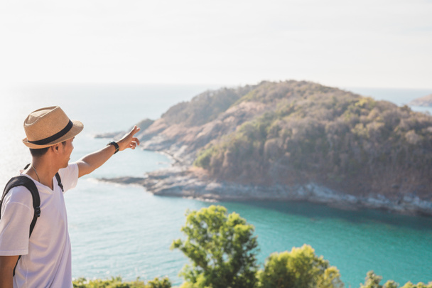 帽子をかぶっている男は幸せそうに手を握っている。男アジアの観光客山と海を見てください日没前にアクティビティライフスタイル屋外の自由または旅行観光インスピレーションのためにバックパッカーの観光客をcovid 19 - 写真・画像